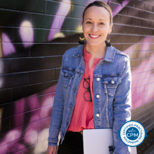 A woman holding a laptop in front of a graffiti wall.